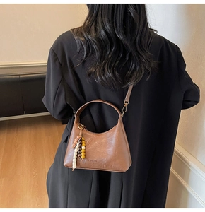 Détails d'un sac demi-lune marron avec une lanière en perles colorées et boucle dorée