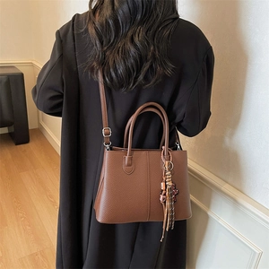 Rear view of a model wearing a brown lychee pattern leather tote bag with tassels