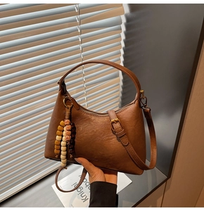 Détail du sac croissant marron avec texture cuir et pendentif en perles colorées