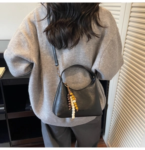 Détail d'un sac à main noir avec perles en bois colorées et logo Chris Bella gravé