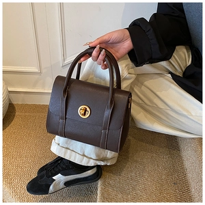 Detail of dark brown leather Boston bag with white stitching and round gold lock