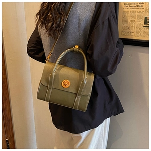 Detail of vintage green frosted leather bag with gold metal twist lock and white stitching
