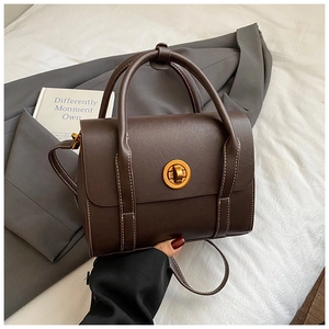 Detail view of dark brown matte leather bag with golden twist lock and white contrast stitching