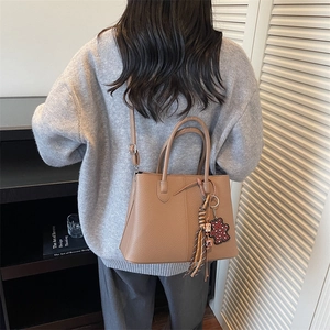 Detailed view of camel faux leather tote with decorative leopard bear and stripe charms
