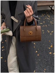 Detail of vintage brown matte leather handbag with gold twist lock and contrast stitching