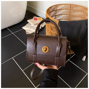 Macro detail of dark brown leather Boston bag with contrast white stitching and gold lock
