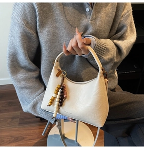 Détail du sac crème avec pompon en perles et fine bandoulière pour un look élégant