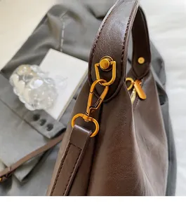 Détails des crochets dorés et du cuir texturé litchi sur le sac à bandoulière