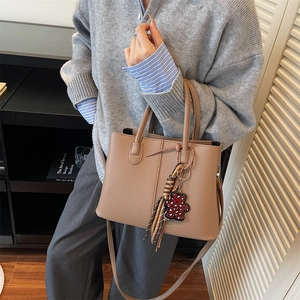 Brown lychee leather tote bag with a leopard print bear charm and detachable strap