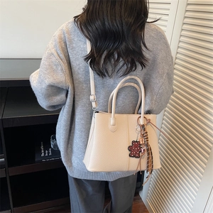 Close-up of beige tote bag with lychee texture and leopard print bear charm detail