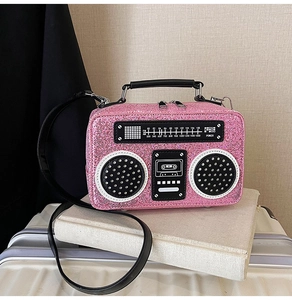 Detail of glitter pink radio-shaped handbag with adjustable strap and vintage dial