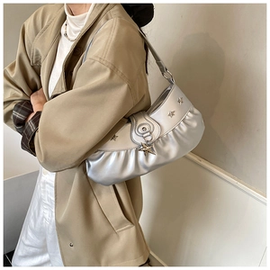 Detail of silver crescent shoulder bag with pleated texture and metallic star charms