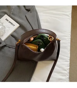 Vue intérieure du sac bandoulière marron montrant le rangement spacieux des objets
