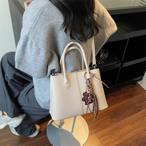 Detail of cream tote bag with litchi texture PU leather and leopard bear charm