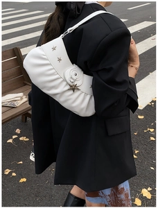Detailed view of white pleated shoulder bag with silver star charms and metallic studs