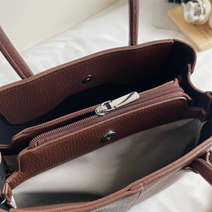 Detail view of large dark brown tote bag interior with three compartments and magnetic clasp