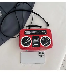 Detailed top view of red glitter radio-shaped crossbody bag with size reference next to a phone