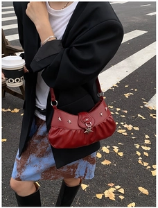 Detail of red leather shoulder bag featuring silver star metal studs and ruched texture