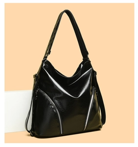 Detailed view of the black glossy hobo bag featuring decorative silver diagonal zippers