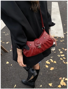 Close-up of wine red pleated leather bag with silver star rivets and star-shaped pendant