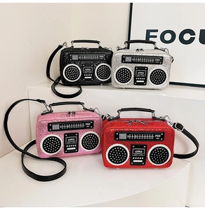 Detail view of radio-shaped crossbody bags in four glitter colors on white pedestals