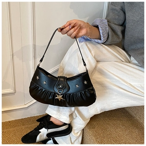 Detail of black crescent hobo bag with pleated leather and gold star studs on strap