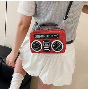 Detail of red glitter radio shaped crossbody bag with vintage dial and black strap