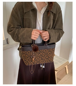 Macro view of leopard print tote bag with brown leather details and stylish tassel charm