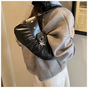 Detail of black pleated hobo bag featuring silver star studs and hanging star pendant