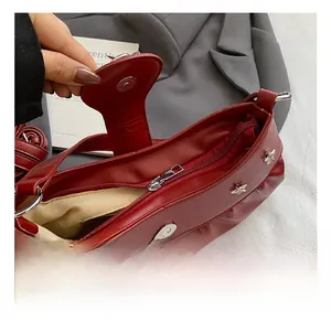 Detail shot of the red ruched shoulder bag featuring gold bee hardware and magnetic closure