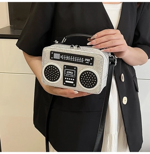 Macro detail of silver sequin radio-shaped bag with black leather handle and zipper