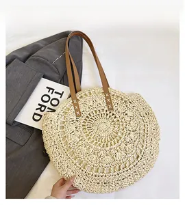 Close-up of circular straw woven bag with intricate openwork pattern and leather strap