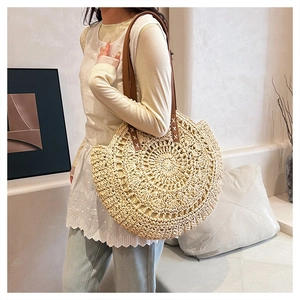 Detail of round straw bag featuring intricate circular crochet and brown leather strap