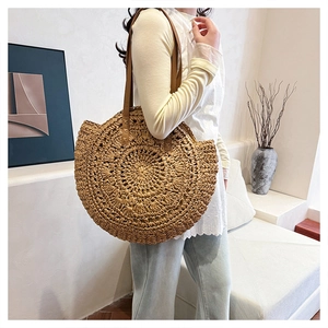 Detailed texture of circular woven straw bag with brown leather shoulder strap and stitching