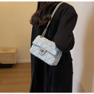 Detail of light blue tweed crossbody bag with golden chain and diamond quilted texture