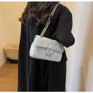 Detail of light blue tweed quilted bag with gold chain strap on a model shoulder