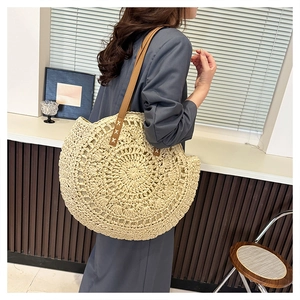 Detail of hand-woven straw tote with brown leather straps and cross-stitch reinforcement