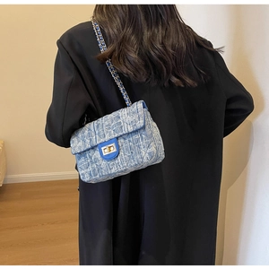 Close-up of blue tweed texture with gold metal twist lock and chain strap detail