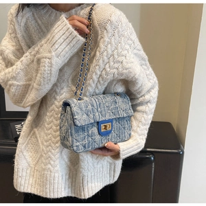 Detail showing the quilted denim texture and metallic twist lock on the blue chain bag