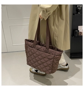 Detail of dark brown quilted nylon tote bag featuring diamond pattern and wide handles