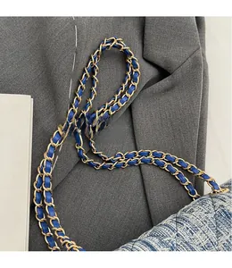 Detailed shot of a luxury tweed shoulder bag with woven blue and gold chain strap