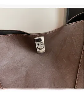 Close-up of silver metal twist lock on brown pebble leather tote bag detail