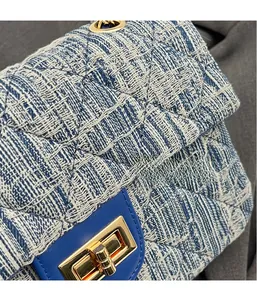 Close-up of blue and white tweed fabric texture with gold twist lock on quilted handbag