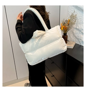 Close-up of white quilted puffer shoulder bag with soft cloud-like texture and wide strap