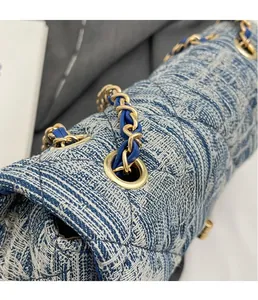 Detail of blue and white tweed shoulder bag with gold hardware and woven chain strap