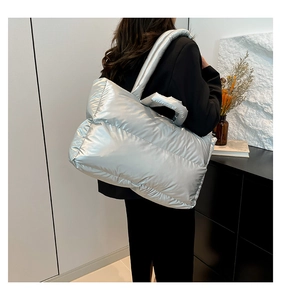 Macro view of metallic silver quilted tote bag with padded texture and sleek handle