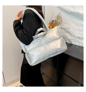 Detail of silver metallic puffer tote bag with quilted texture and double shoulder straps