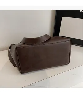 Detailed view of the flat bottom stitching and thick PU leather texture on brown tote bag