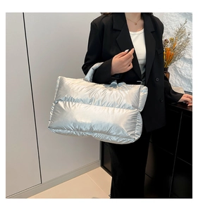 Close-up of large metallic silver quilted handbag with soft padded texture and top handles