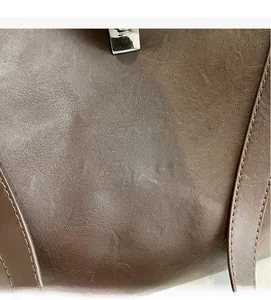 Close-up of deep brown leather tote bag showing textured surface and silver metal clasp